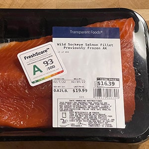 Closeup of a salmon steak with a FreshScore label on the outer packaging