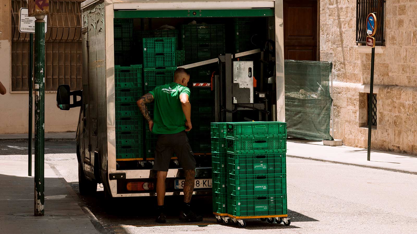 Man loading truck with plastic bins. 