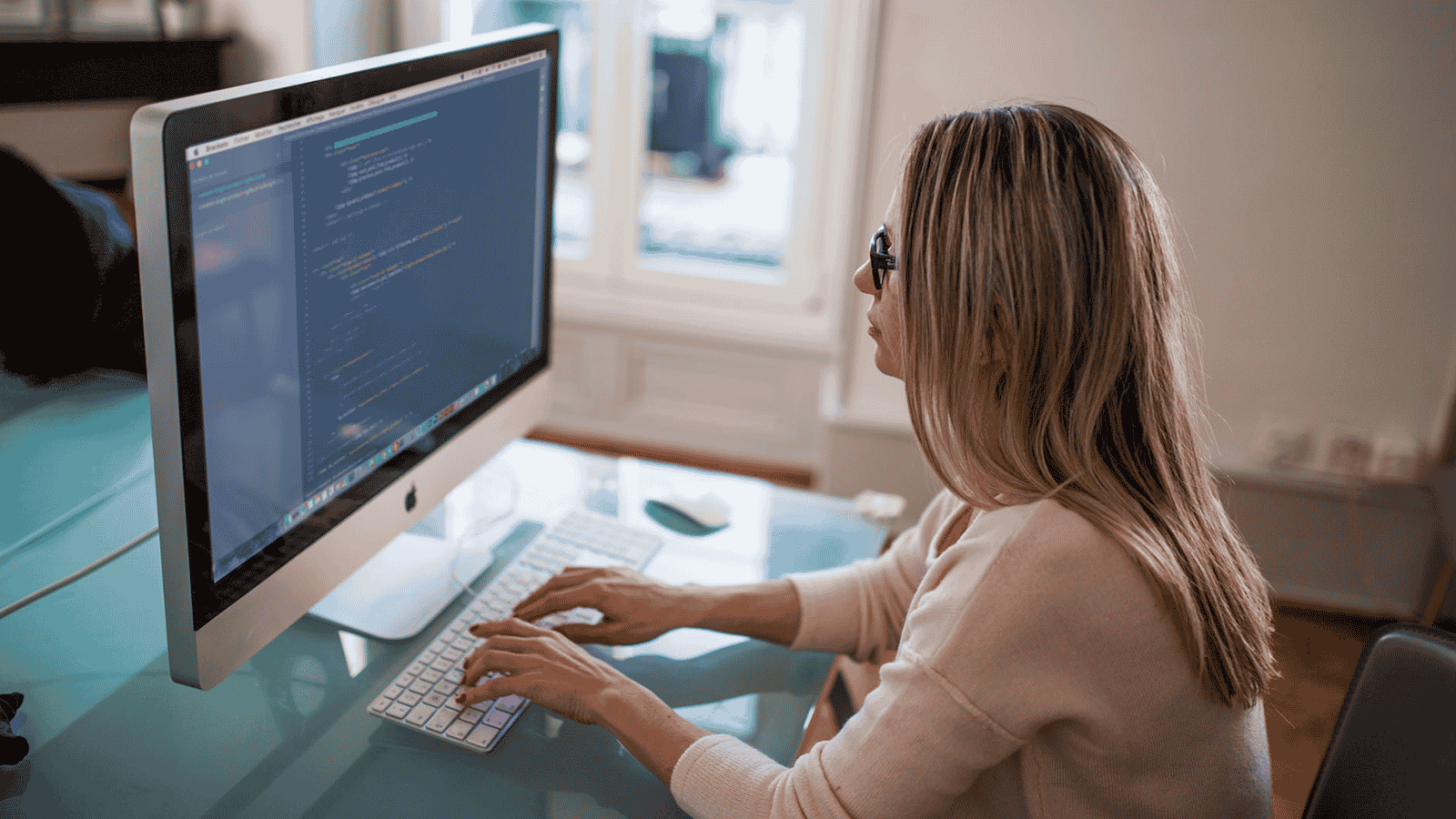 Photo of a woman creating source code on a desktop computer